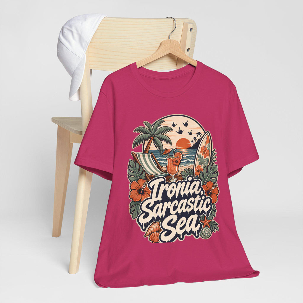The "Ironia, Sarcastic Sea" retro beach T-shirt by SarcasmArt in raspberry pink hanging on a wooden chair.