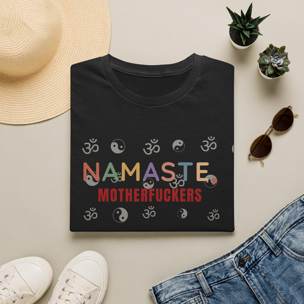 Flat lay of the Black "Namaste, Motherfuckers" funny yoga T-shirt by SarcasmArt with a sun hat, sunglasses and denim – front print with colorful lettering and yoga icons.
