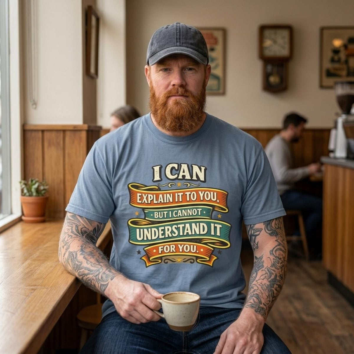 Bearded man in a cap holding a coffee in a café, wearing the "I Can Explain It to You, But I Can't Understand It for You" sarcastic teacher T-shirt by SarcasmArt in Blue Jean.