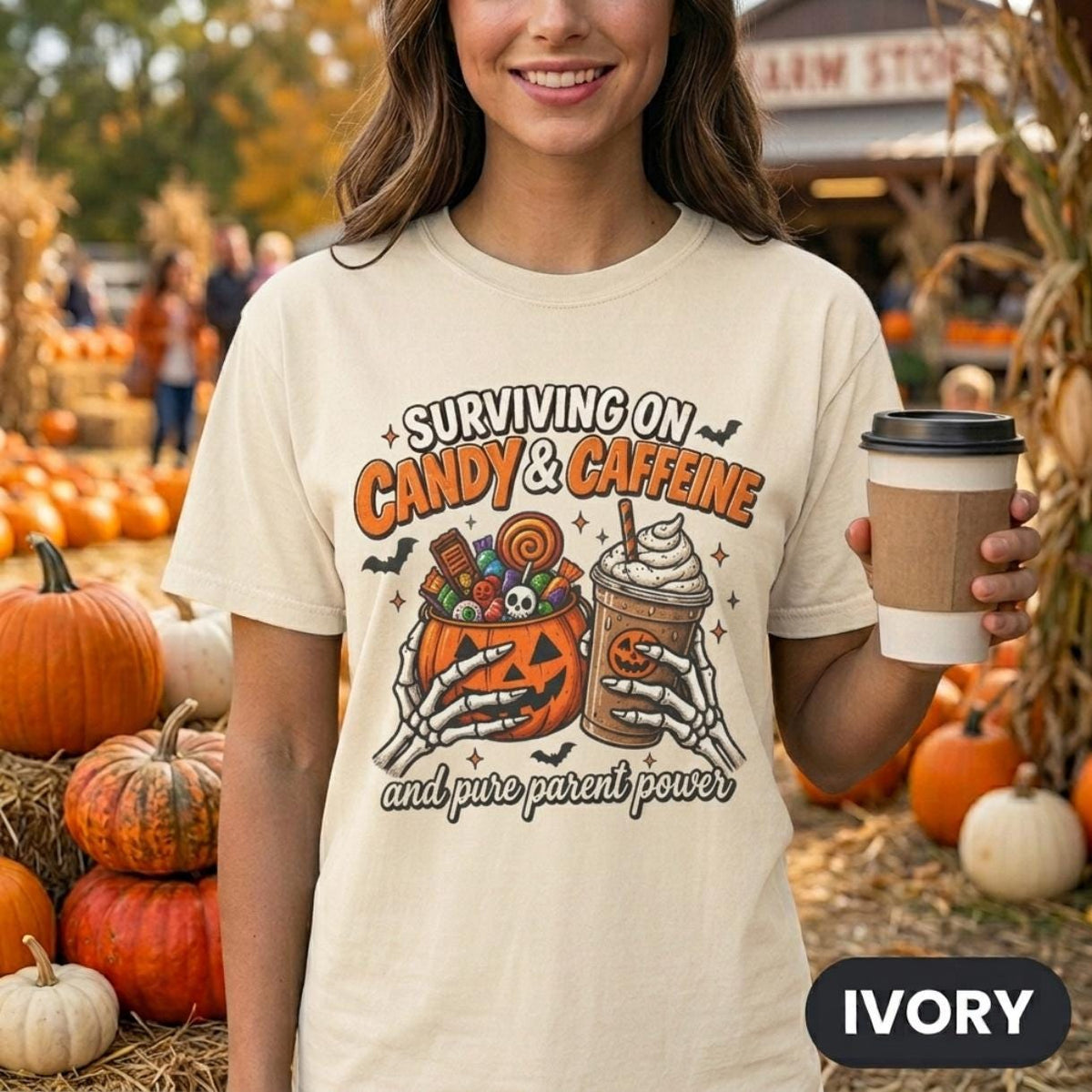Woman holding a coffee at a pumpkin patch wearing the "Surviving on Candy & Caffeine" Halloween mom T-shirt by SarcasmArt in Ivory – a funny tired parent shirt.