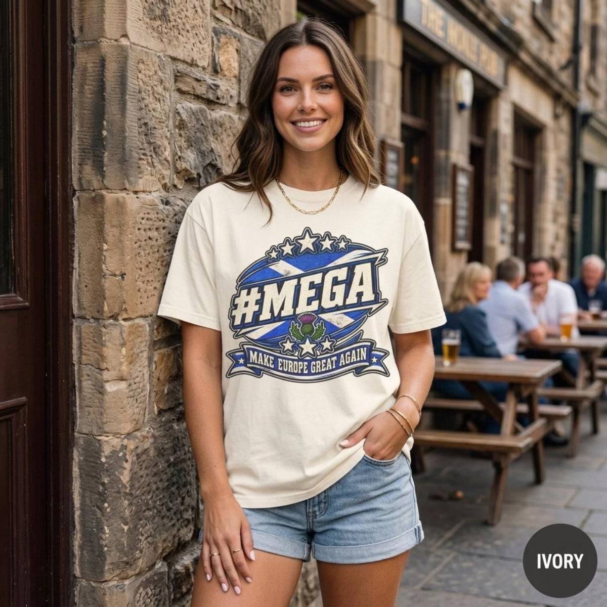 Smiling woman outside a pub in a Scottish old town wearing the "#MEGA Make Europe Great Again" Scotland T-shirt by SarcasmArt in Ivory.