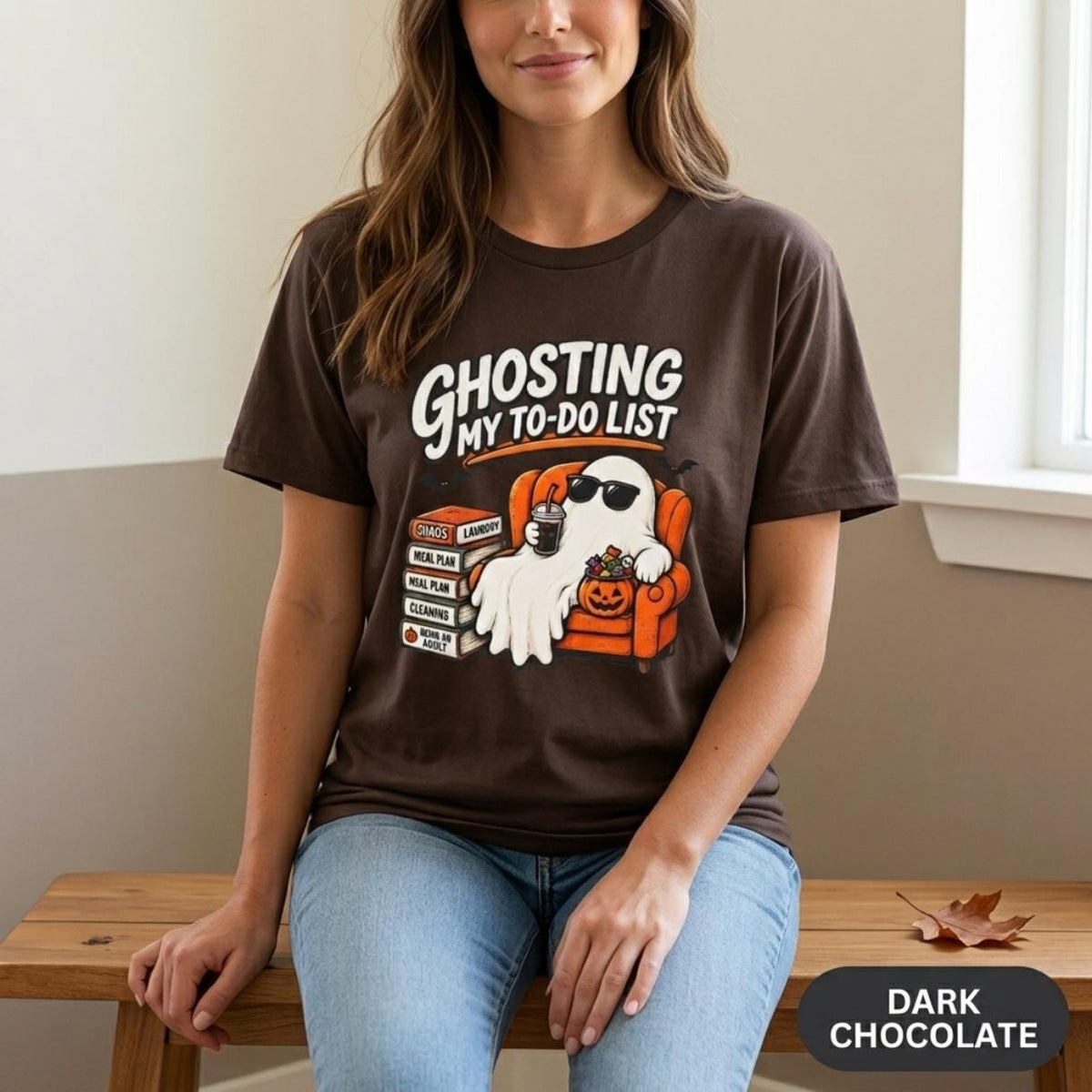 Woman sitting on a bench wearing the "Ghosting My To-Do List" retro Halloween procrastinator T-shirt by SarcasmArt in Dark Chocolate.