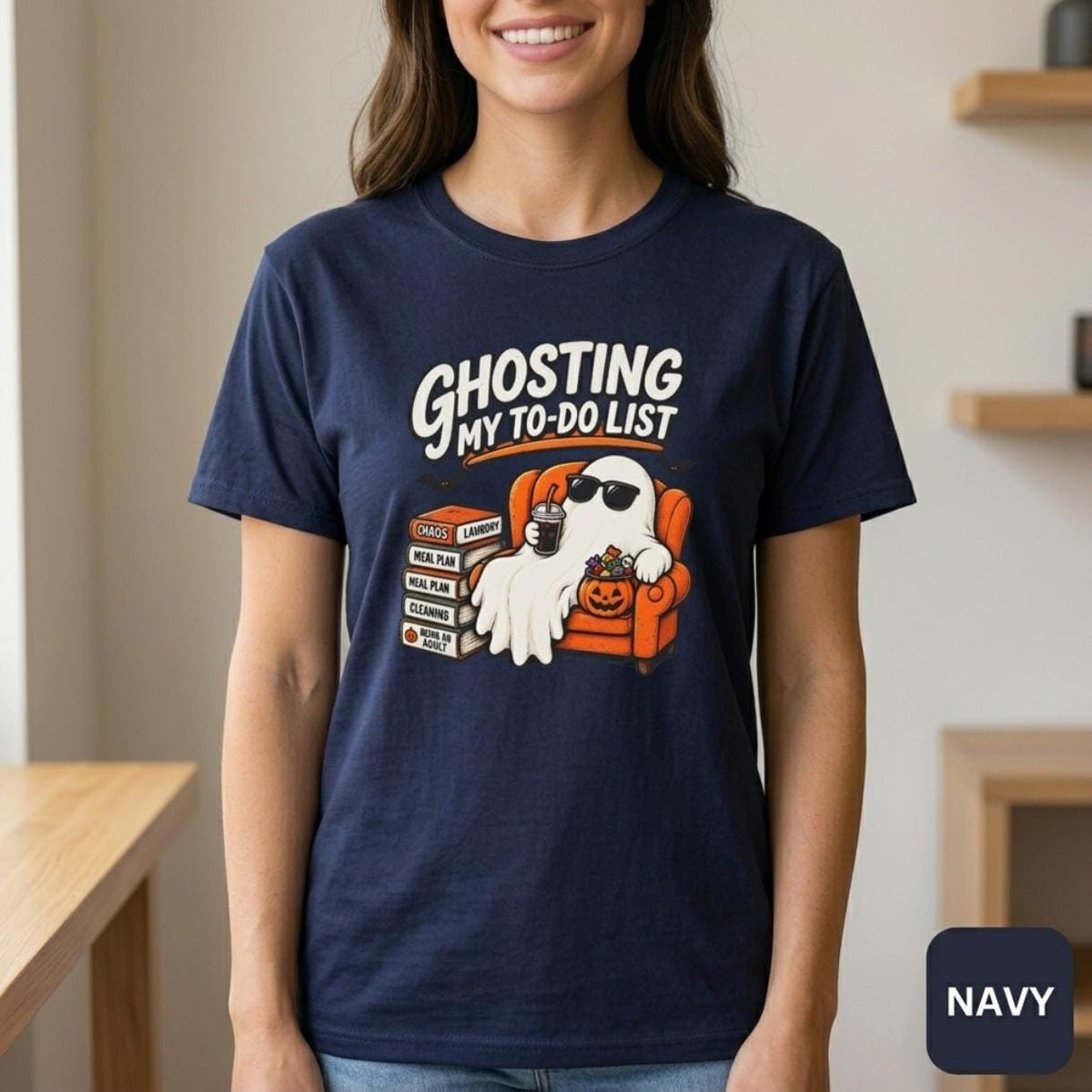 Woman in a kitchen wearing the "Ghosting My To-Do List" retro Halloween procrastinator T-shirt by SarcasmArt in Navy – a funny spooky season shirt.