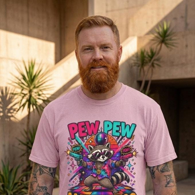 Bearded man wearing the "Pew Pew Madafakas" raccoon meme T-shirt by SarcasmArt in Blossom (soft pink).