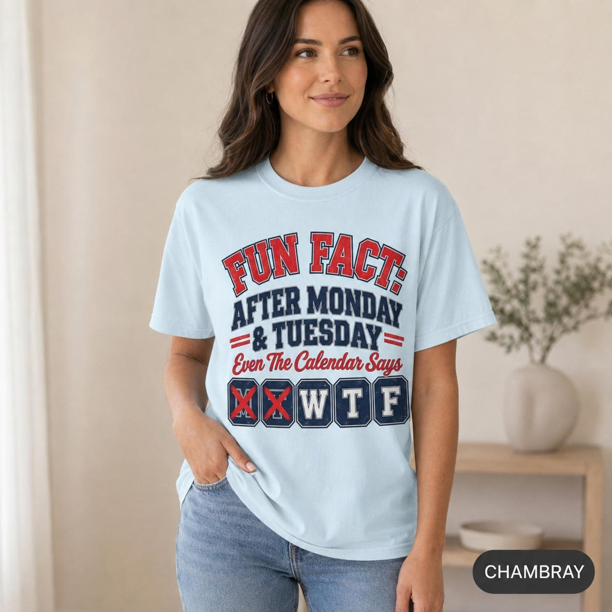 Smiling woman wearing the "Fun Fact: After Monday & Tuesday" WTF varsity work T-shirt by SarcasmArt in Chambray (light blue) – a sarcastic coworker gift.