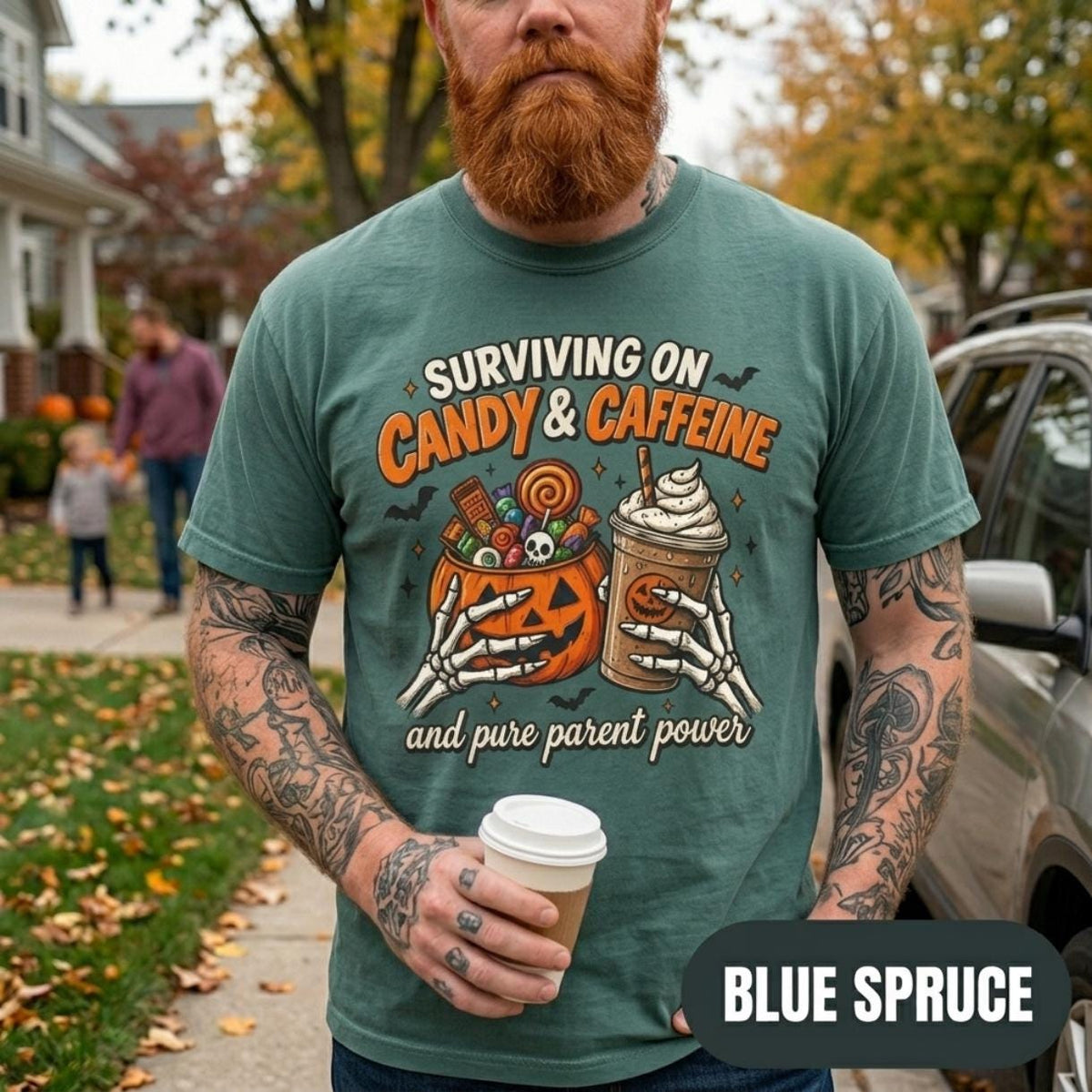 Bearded man with a coffee on an autumn street wearing the "Surviving on Candy & Caffeine" Halloween mom T-shirt by SarcasmArt in Blue Spruce.
