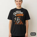 Woman wearing the "Runs on Caffeine & Chaos" skeleton coffee Halloween T-shirt by SarcasmArt in Black against a white wall – the cream and orange skeleton print stands out on the dark tee.