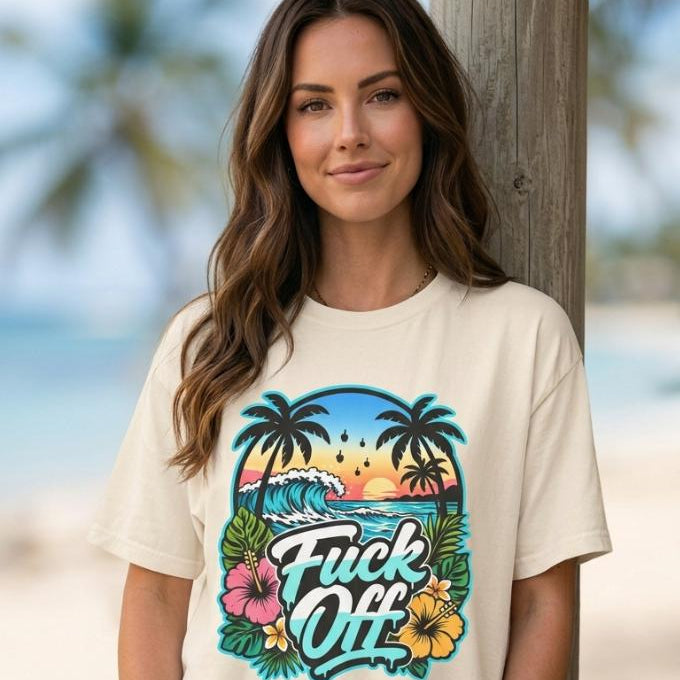 Woman on a sunny beach wearing the "F*ck Off" retro tropical beach T-shirt by SarcasmArt in Natural – a sarcastic vacation shirt.