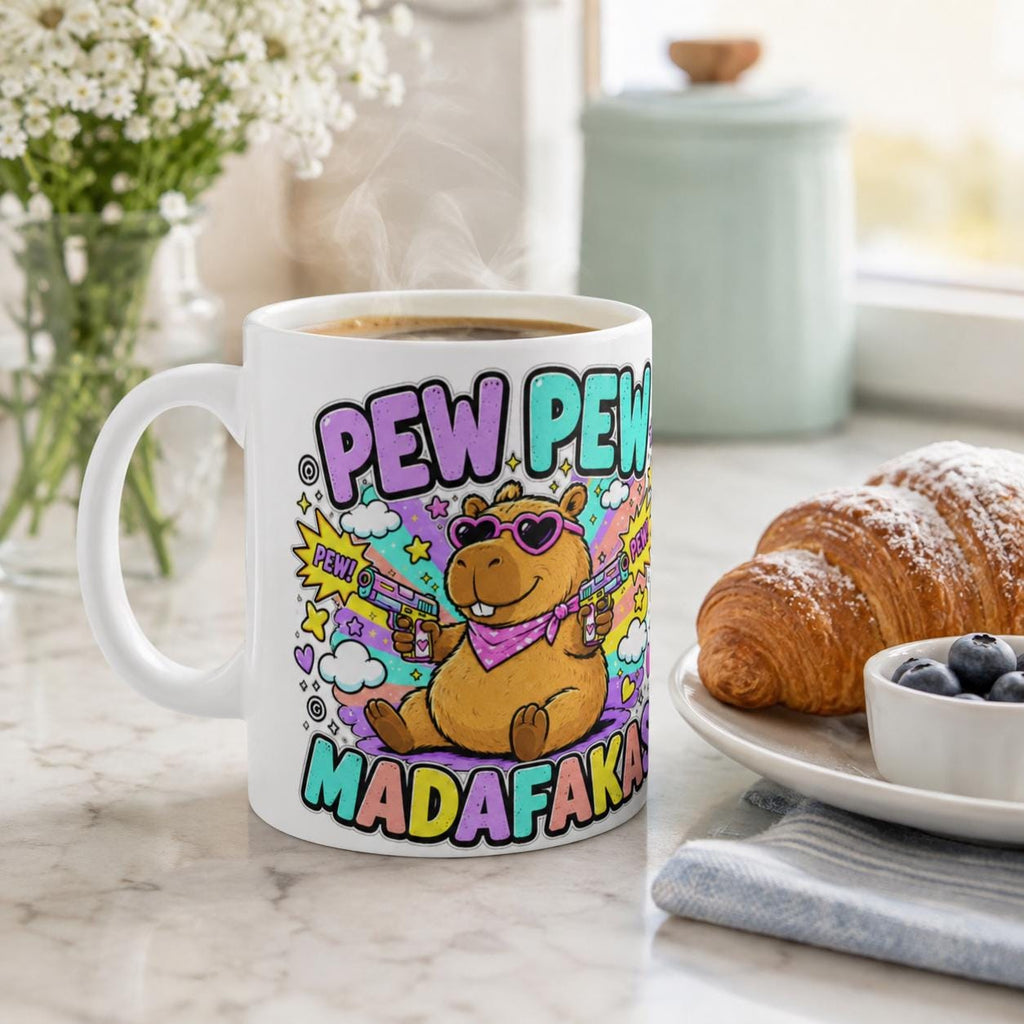 The "Pew Pew Madafakas" capybara coffee mug by SarcasmArt on a breakfast table with a croissant and berries – a meme mug for capybara lovers.