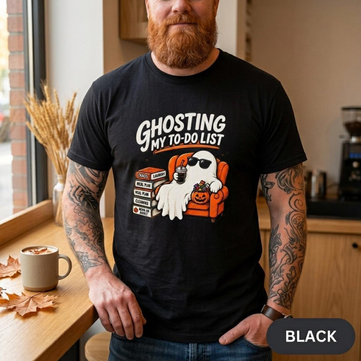 Bearded man in a café wearing the "Ghosting My To-Do List" retro Halloween procrastinator T-shirt by SarcasmArt in Black.