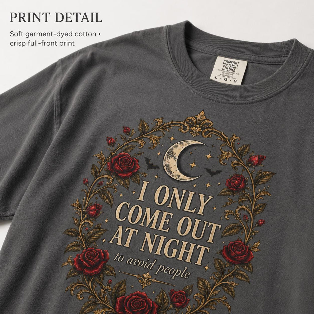 Print detail of the "I Only Come Out at Night" romantic gothic vampire T-shirt by SarcasmArt on Pepper (washed charcoal): a crescent moon, bats and dark red Victorian roses in a gold filigree frame around the words I ONLY COME OUT AT NIGHT, on soft garment-dyed Comfort Colors 1717 cotton.