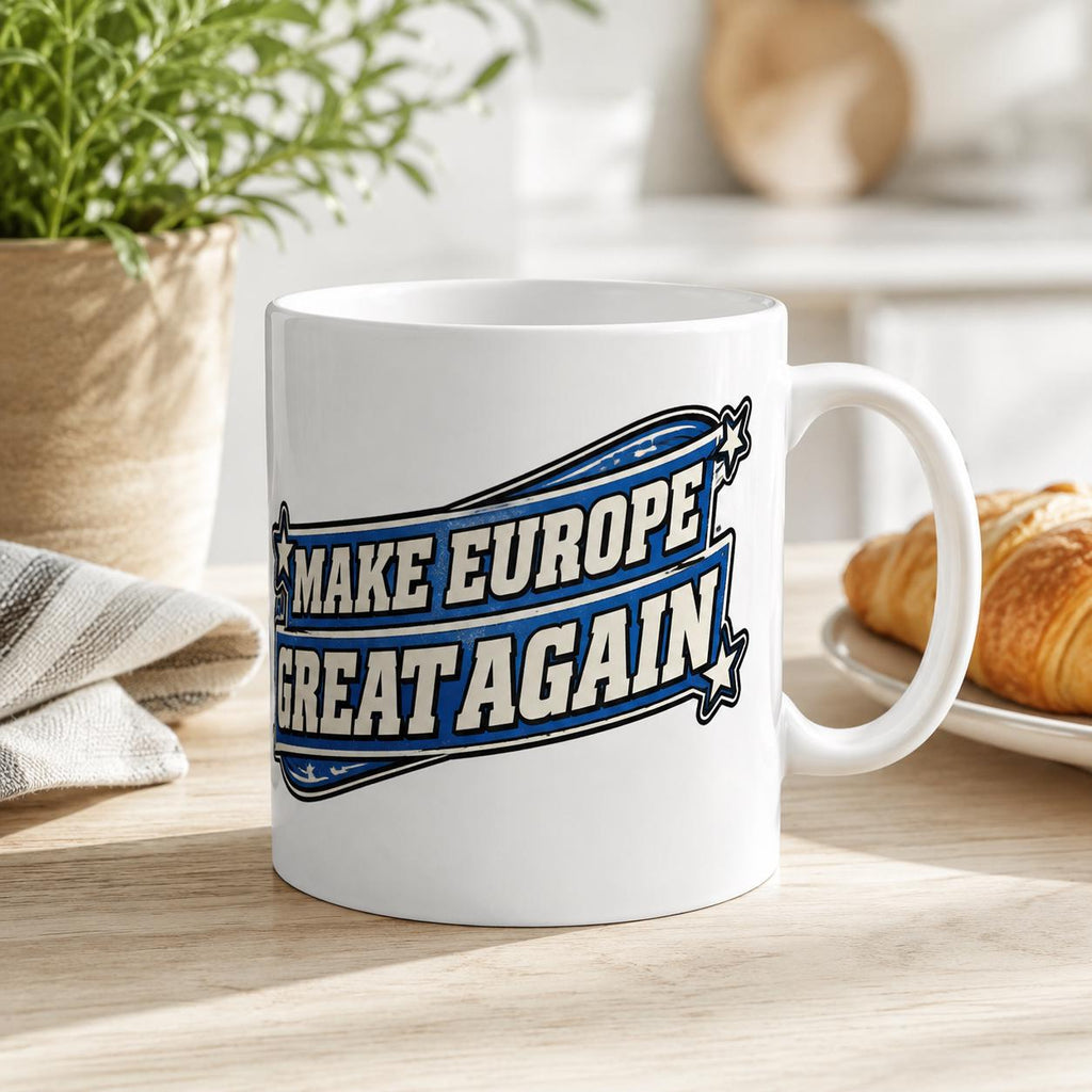 Scotland Mug – Make Europe Great Again Coffee Cup by SarcasmArt. A white ceramic mug featuring a blue and black graphic design with the text "MAKE EUROPE GREAT AGAIN" enclosed within a stylized banner shape, accented by small stars on the left and right sides of the text block.