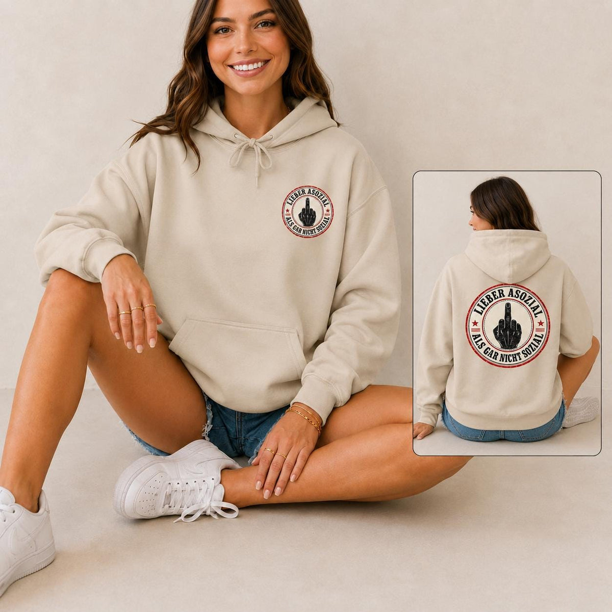 Woman sitting on the floor wearing the "Lieber asozial als gar nicht sozial" middle finger hoodie by SarcasmArt in Sand, with an inset of the back print – a Gildan Heavy Blend 18500 hooded sweatshirt with a small round chest badge and a large back print with a middle finger hand and the German slogan LIEBER ASOZIAL ALS GAR NICHT SOZIAL (better antisocial than not social at all).