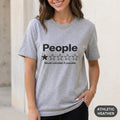 Woman wearing the "People – 1 Star, Would Uninstall If Possible" funny review T-shirt by SarcasmArt in Athletic Heather (grey).