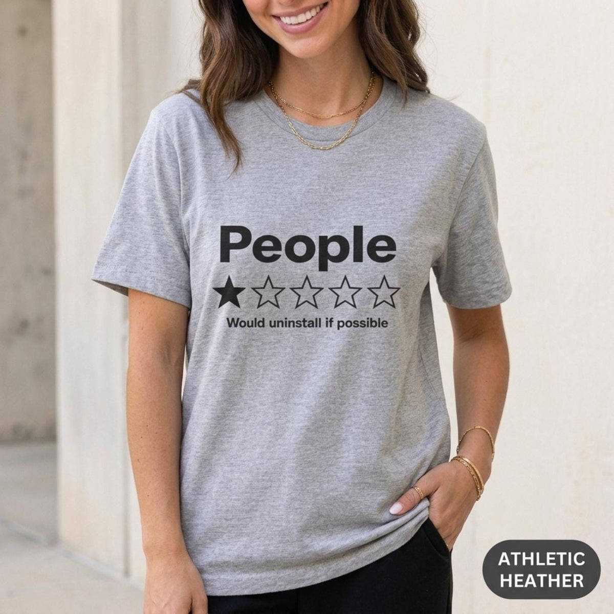 Woman wearing the "People – 1 Star, Would Uninstall If Possible" funny review T-shirt by SarcasmArt in Athletic Heather (grey).