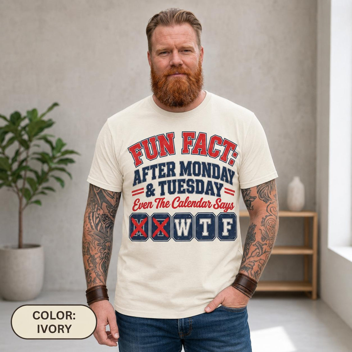 Bearded man wearing the "Fun Fact: After Monday & Tuesday" WTF varsity work T-shirt by SarcasmArt in Ivory, showing the red and navy varsity print.