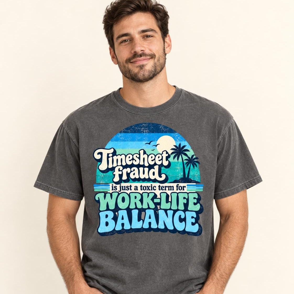 Smiling man wearing the "Timesheet Fraud Is Just a Toxic Term for Work-Life Balance" sarcastic work T-shirt by SarcasmArt in Pepper (washed charcoal), showing the retro sunset work-life balance print.