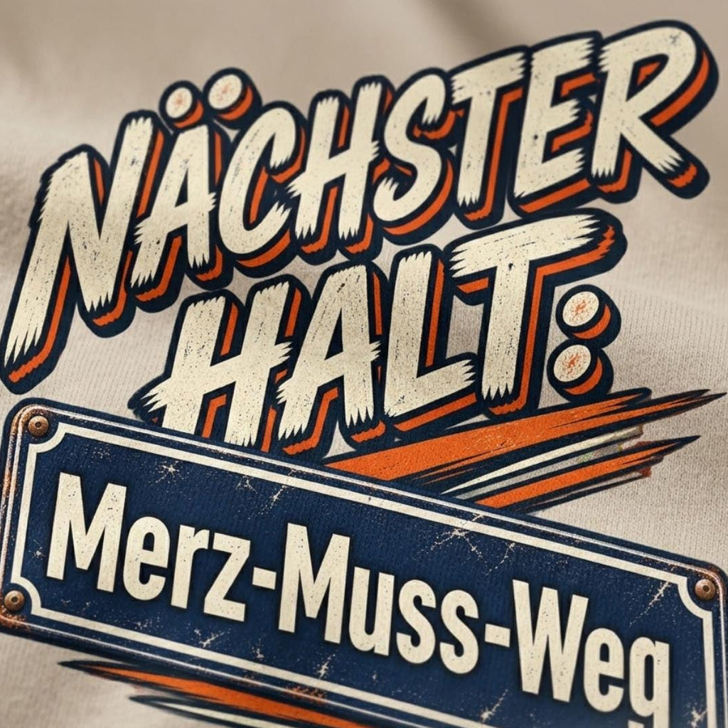 Print detail of the "Nächster Halt: Merz-Muss-Weg" German political satire T-shirt by SarcasmArt: retro comic lettering NÄCHSTER HALT: above a blue street-sign style plate reading Merz-Muss-Weg with orange speed lines.