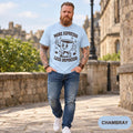 Bearded man walking in a historic old town wearing the "More Espresso, Less Depresso" retro coffee T-shirt by SarcasmArt in Chambray (light blue).