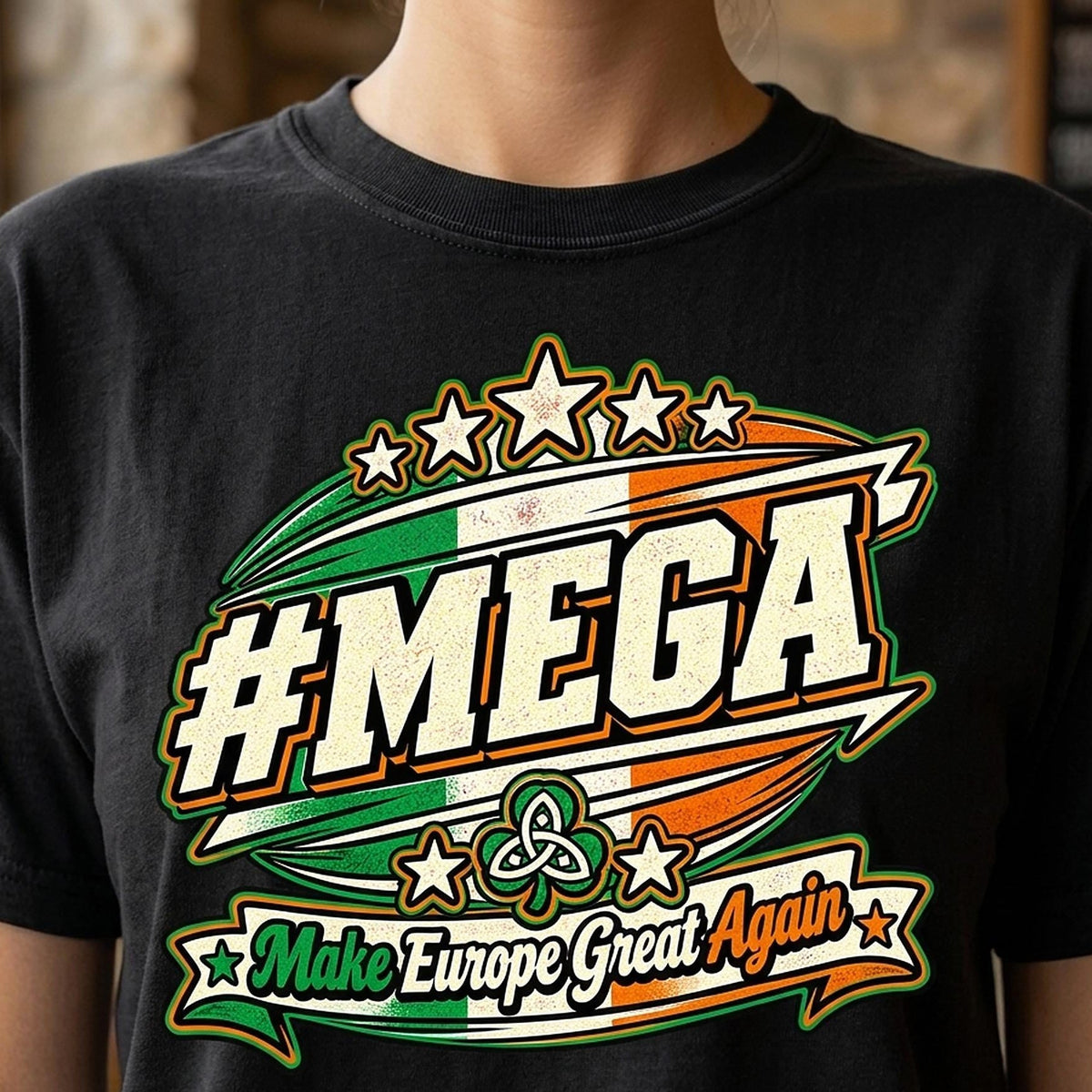 Close-up of the "#MEGA Make Europe Great Again" Ireland T-shirt by SarcasmArt in Black: a retro #MEGA sports badge with the green-white-orange Irish tricolour, a Celtic trinity knot, stars and a Make Europe Great Again script banner, printed large on a garment-dyed Comfort Colors 1717 tee.