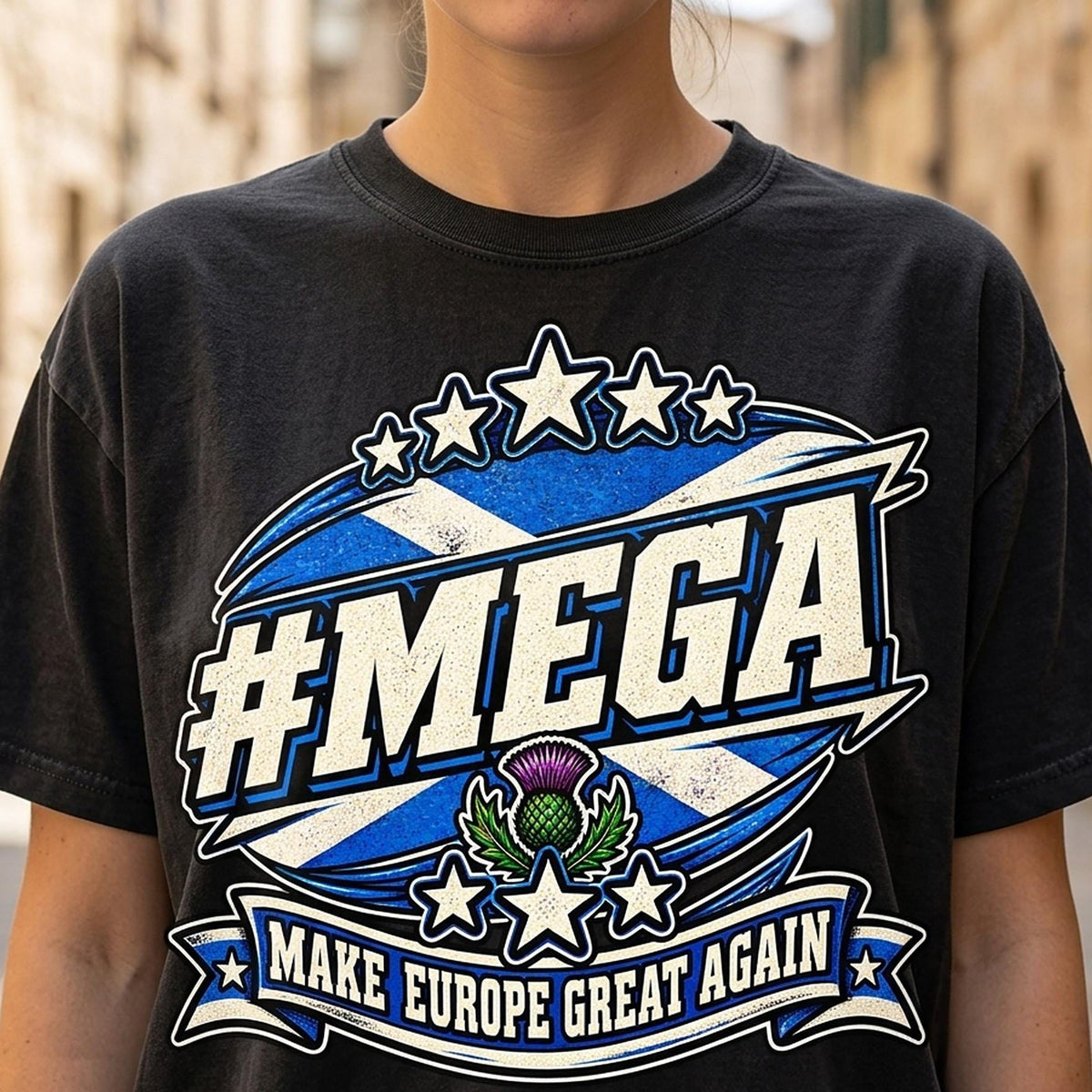 Close-up of the "#MEGA Make Europe Great Again" Scotland T-shirt by SarcasmArt in Black: a retro #MEGA sports badge with the blue-and-white Scottish saltire, a purple thistle, stars and a MAKE EUROPE GREAT AGAIN banner, printed large on a garment-dyed Comfort Colors 1717 tee.