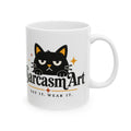 May include: A white ceramic mug featuring a black cat illustration with an annoyed expression. Below the cat, the text reads SarcasmArt in a bold font, followed by the phrase SAY IT. WEAR IT. in smaller capital letters with orange star accents.