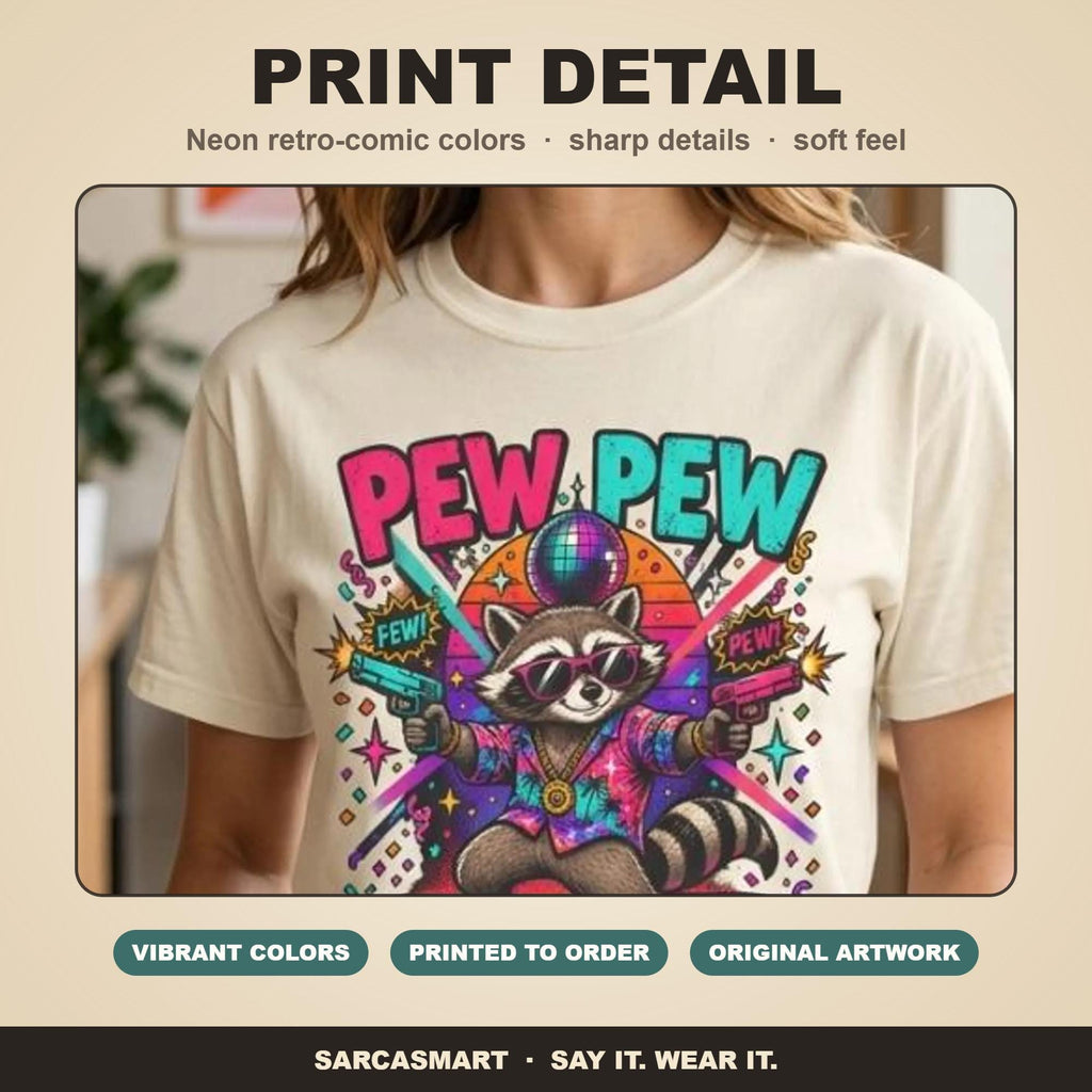 Print detail of the "Pew Pew Madafakas" raccoon meme T-shirt by SarcasmArt: bold retro neon colors, sharp details and a soft feel on garment-dyed cotton.