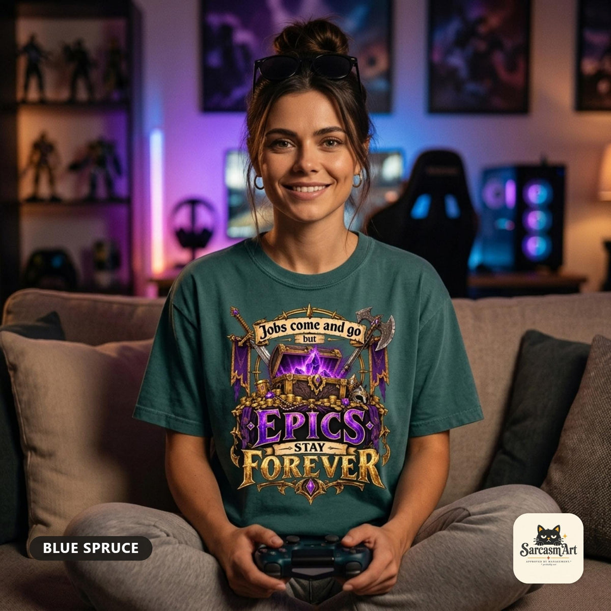 Woman holding a game controller on a sofa in a neon-lit gaming room wearing the "Epics Stay Forever" funny gamer T-shirt in Blue Spruce – a Comfort Colors 1717 unisex tee by SarcasmArt with the quote "Jobs come and go but EPICS STAY FOREVER" above a glowing purple loot chest in a gold fantasy frame with crossed axes.