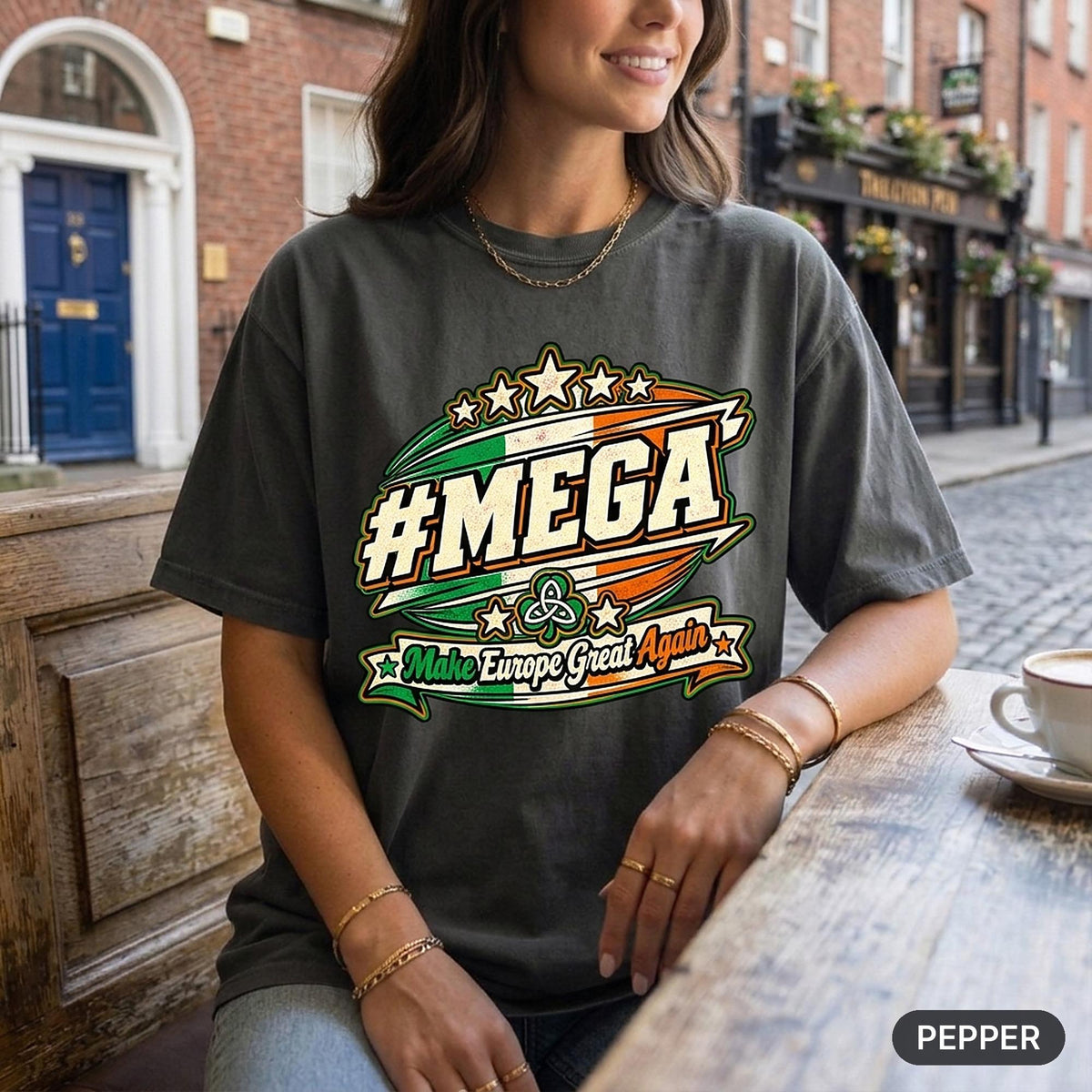 Woman holding a coffee at a café terrace wearing the "#MEGA Make Europe Great Again" Ireland T-shirt by SarcasmArt in Pepper.