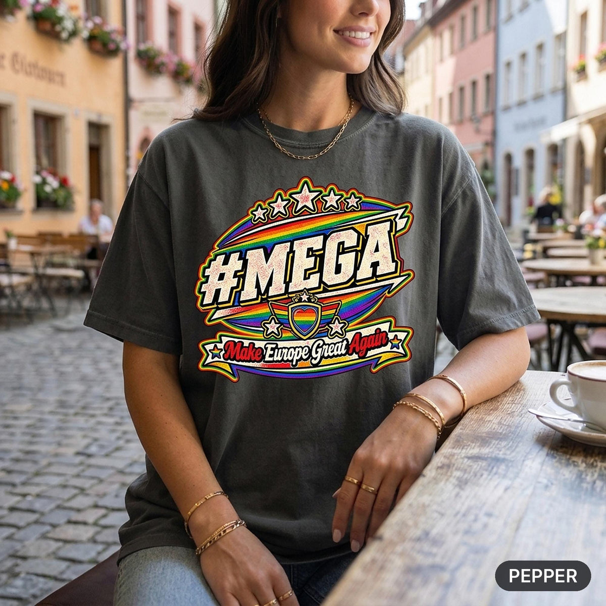 Woman with a coffee at a street café wearing the "#MEGA Make Europe Great Again" Rainbow Pride T-shirt by SarcasmArt in Pepper.