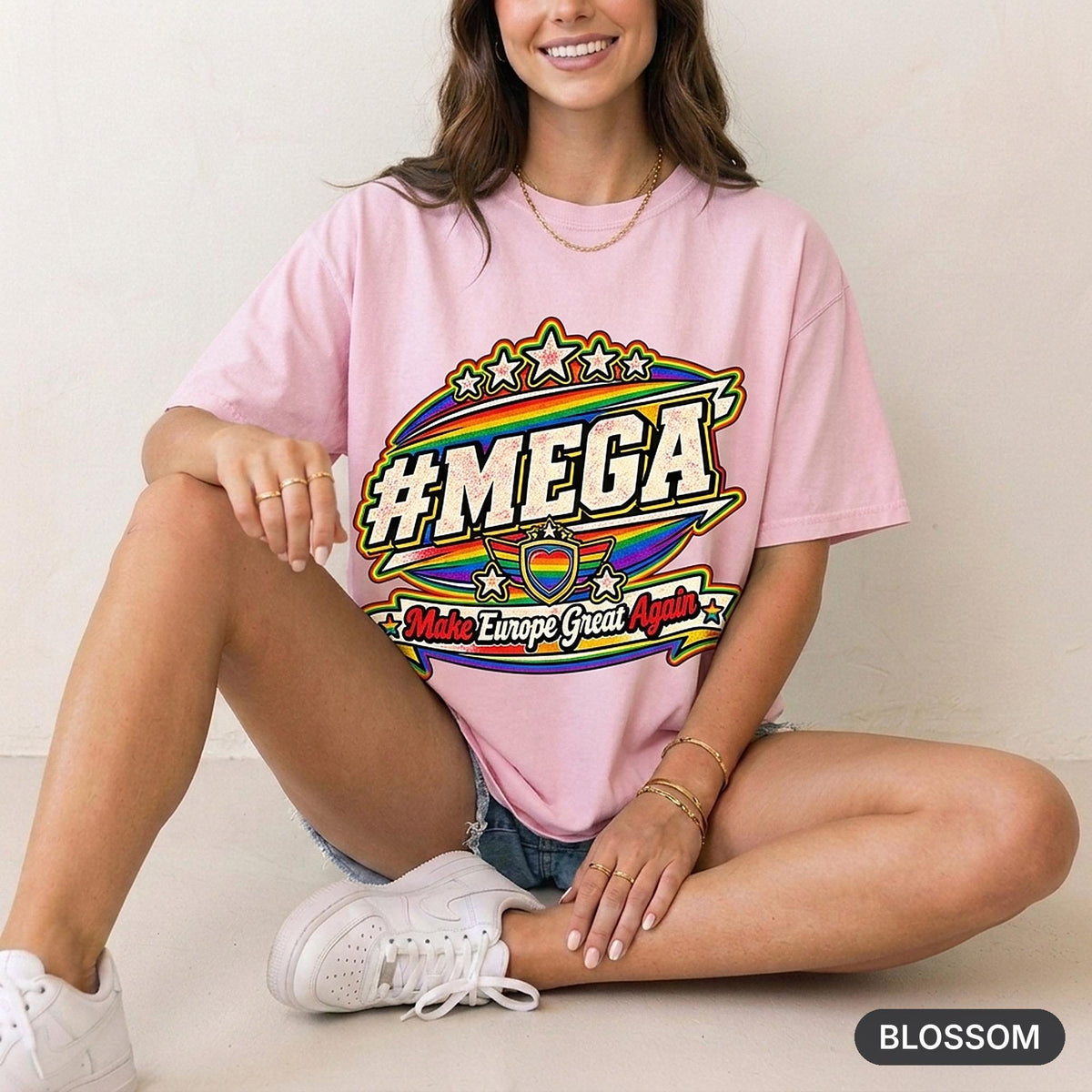 Woman sitting on a stool in a bright studio wearing the "#MEGA Make Europe Great Again" Rainbow Pride T-shirt by SarcasmArt in Blossom.