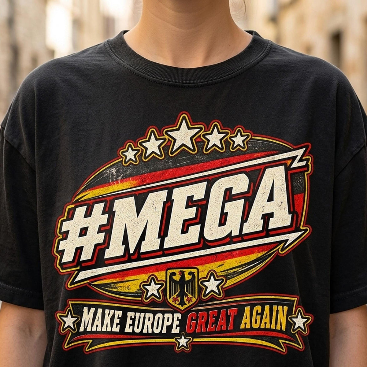 Close-up of the "#MEGA Make Europe Great Again" Germany T-shirt by SarcasmArt in Black: a retro #MEGA sports badge with black-red-gold German flag stripes, a German eagle shield, stars and a MAKE EUROPE GREAT AGAIN banner with GREAT in red, printed large on a garment-dyed Comfort Colors 1717 tee.