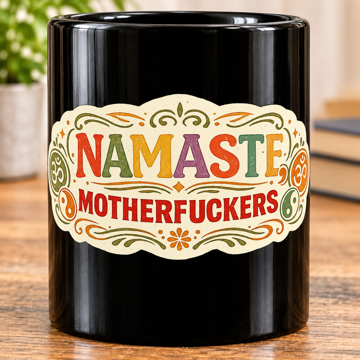 Print close-up of the "Namaste Motherfuckers" funny yoga coffee mug by SarcasmArt: colorful boho mandala label with om and yin-yang symbols and the adult-humor phrase NAMASTE MOTHERFUCKERS on glossy black ceramic.